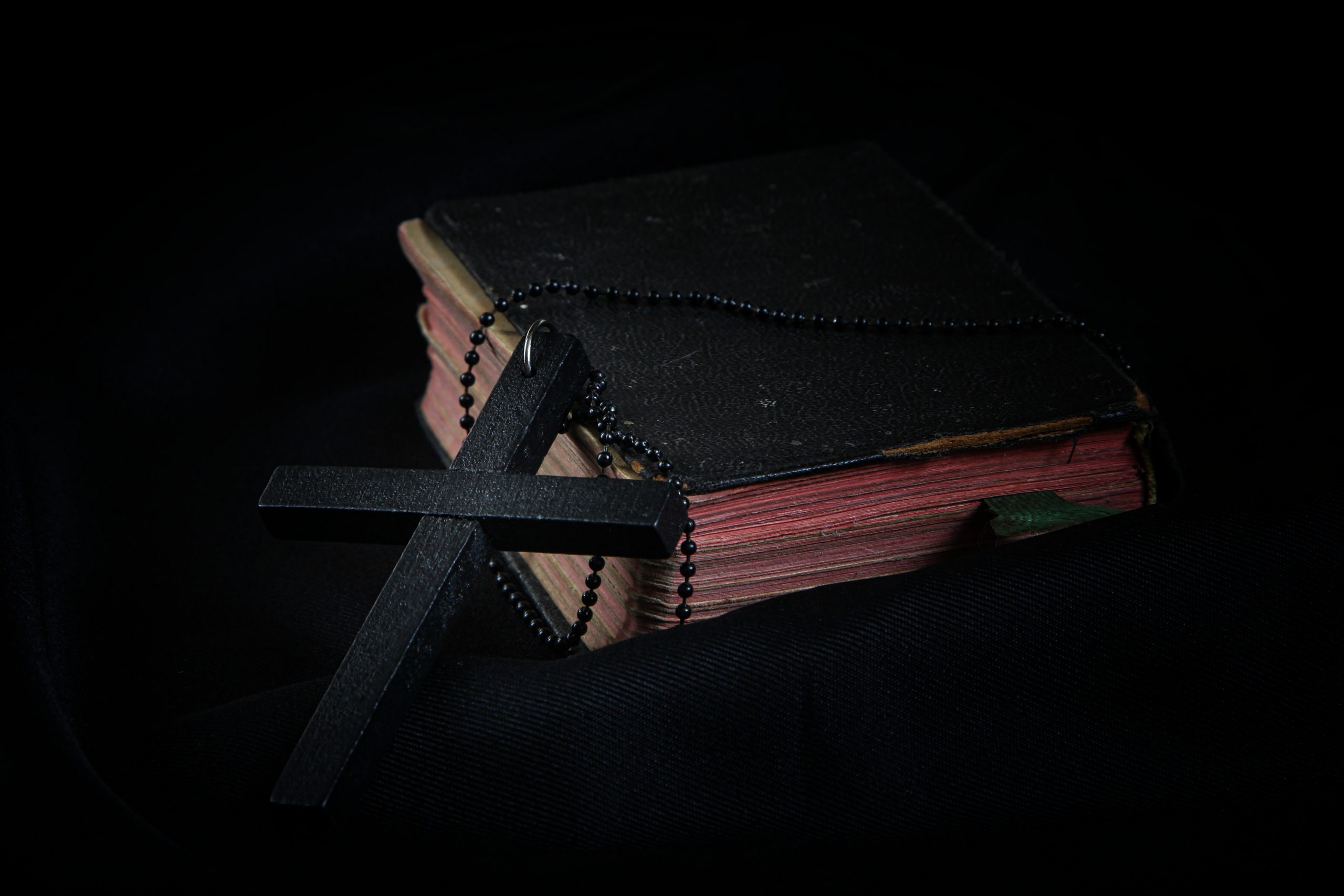 black-cross-leaning-on-black-hardcover-bible-3822681