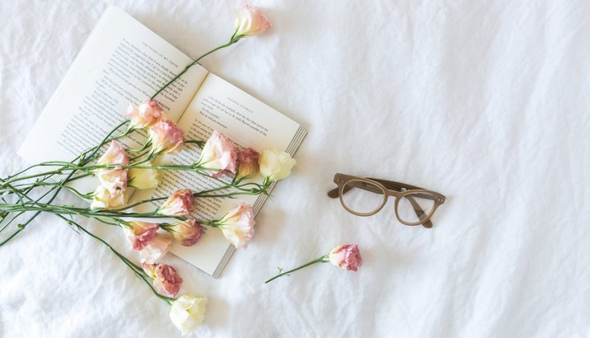 white-and-pink-flowerson-a-book-beside-eyeglasses-545042