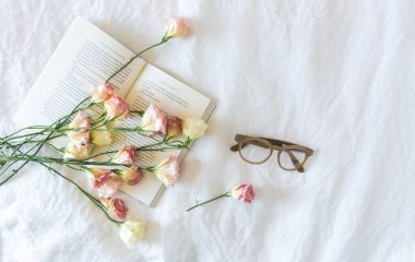 white-and-pink-flowerson-a-book-beside-eyeglasses-545042